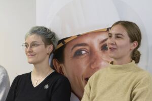 Zwei Teilnehmerinnen der Career Connect lehnen an der Wand und hören den Unternehmen zu.